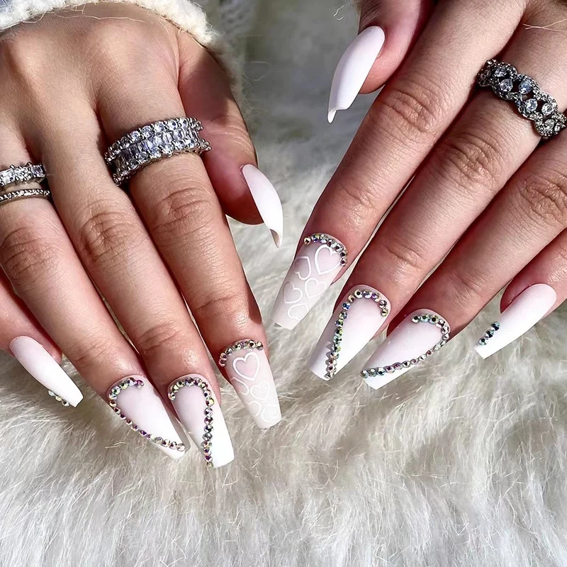 Kunstvolle Nagelverlängerungen mit Herzen-Design und Glitzerakzenten Karnz