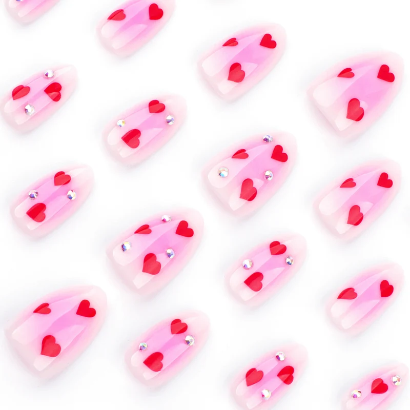 Kunstvolle Nagelkunst mit Herzmotiven und glamourösen Details Karnz