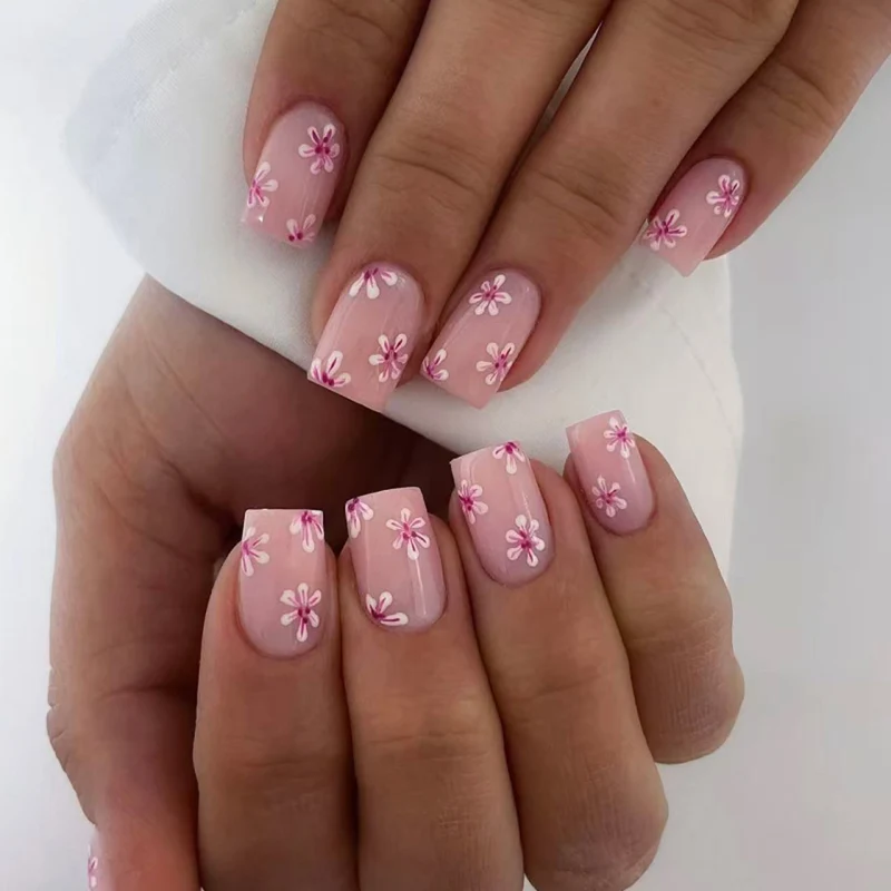 Kunstvolle Nagelkunst mit Blumen-Design und Blauem French Tip Karnz