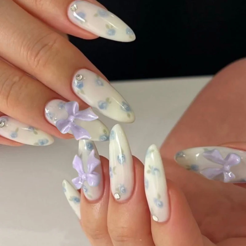 Kunstvolle Nagelkunst mit Blumen-Design und Blauem French Tip Karnz