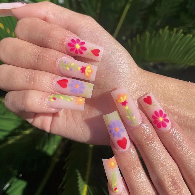 Kunstvolle Gel-Nägel mit elegantem Floral-Design und Glitzerakzenten Karnz