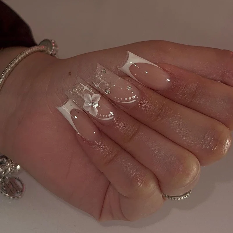 Elegante Kunstnägel mit floralen Designs und Glitzerakzenten Karnz